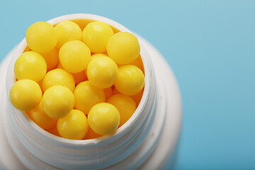 Vitamins are yellow in a white jar on a blue-blue background.