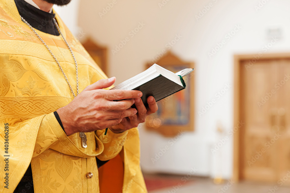 Wall mural Orthodox Church. Christianity. Priest hands holding Holy Bible book in traditional Orthodox Church background on wedding day, Easter Eve or Christmas celebration. Religion faith pray symbol