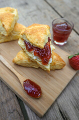Close up Scones with Clotted cream and Strawberry Jam  in a wooden plate on a wood table. 
