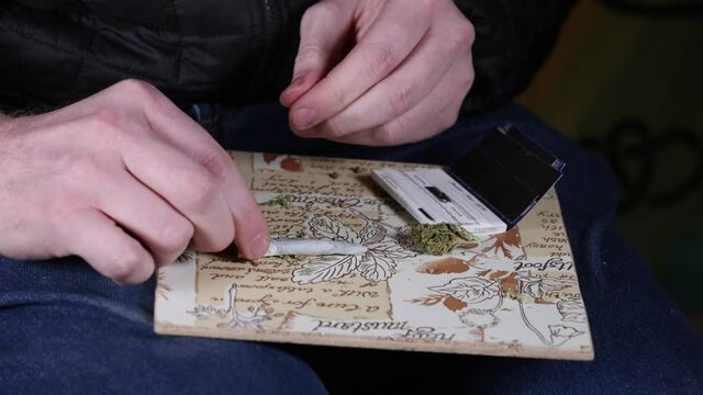 Joint on a board next to a marijuana flower and rolling papers