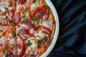 round pizza in a white plate on a dark background