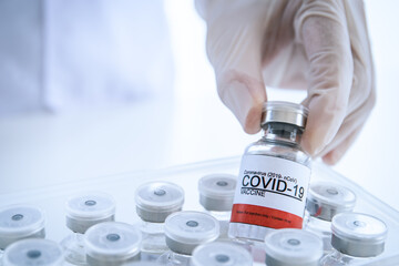 Doctor picking up a COVID-19 or Coronavirus vaccine from a box.
