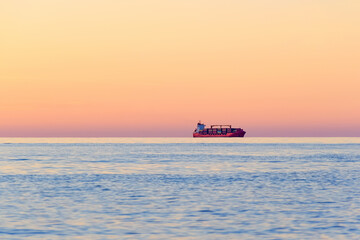 Container Cargo ship on the horizon at sunset.