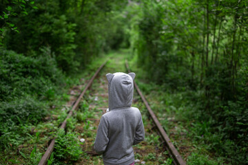 Kid on abandoned railroad track in the forest. Focus on kid.