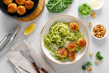 Chicken meatballs with pasta and green kale cashew pesto sauce, top view