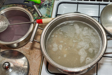 Saucepan with boiling broth on white stove