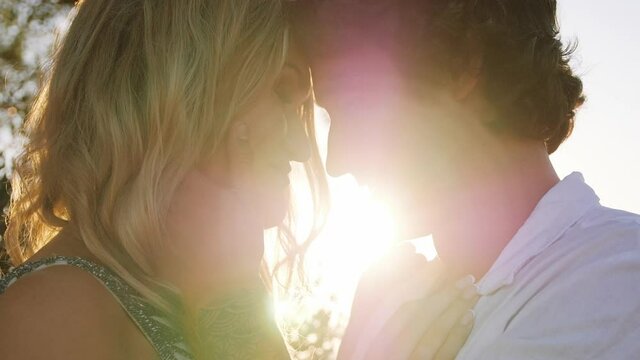 Lovers displaying their affection, hugged smiling under golden sunset  - close up