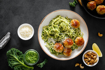 Chicken meatballs with pasta and green kale cashew pesto sauce, top view