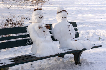 Schneemann und Schneefrau auf einer Parkbank