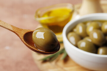 Composition of green olives in oil, olive branch, gravy boat on the background. Space for text.
