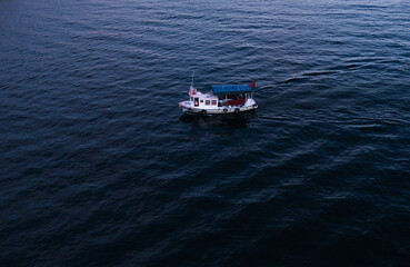 Aerial drone bird's eye top view photo of small boat.  A fishing boat sails along a calm river or sea.