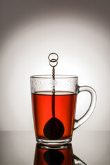Black tea in a glass cup with a handle and a teaspoon. Photo taken in studio