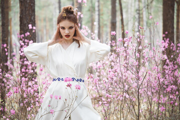 Japanese-style girl in a flowering forest among pink flowers in spring