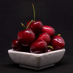 Fresh cherries in bowl on black background