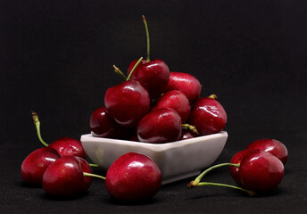 Fresh cherries in bowl on black background