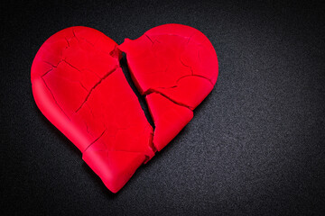 Broken and broken red heart on a black background. Closeup. Vignette. Valentine's Day