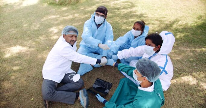 Female and male medical staff taking a break seated on grass outdoors celebrate have fun taking a break to enjoy victory hard work bonding over the dark times in positive emotions cool attitude 