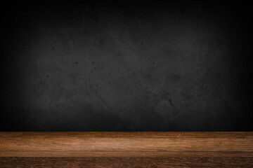 Free space on a wooden table for displaying products with a blurred black wall background.