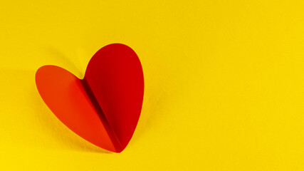 Beautiful folded red heart on a yellow background. Close-up. Minimalism. Valentine's day