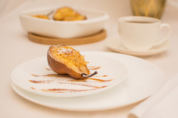 Baked pears with nuts and cheese on a white ceramic plate with caramel.