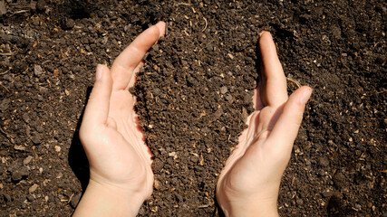 Top view of female hands holding garden ground and lifting up. Concept of environment protection...
