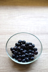 Bowl of blueberries on wooden table. Selective focus.