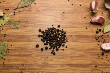 Allspice on a wooden background. Garlic and bay leaf. View from above. Seasoning flavoring for meat and food..