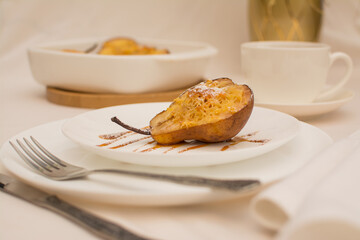 Baked pears with nuts and cheese on a white ceramic plate with caramel.