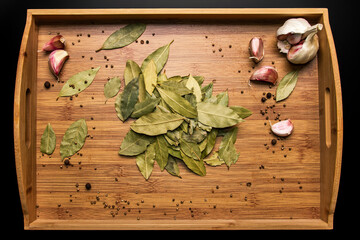 Bay leaf on a wooden background. Garlic and pepper in a pot. View from above. Seasoning flavoring for meat and food..