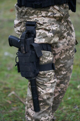 Close-up of a pistol with a silencer in a holster on the leg of a soldier