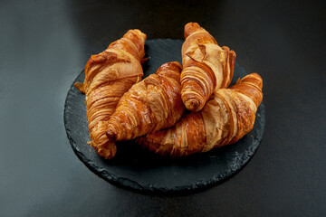 Appetizing baked croissant on a dark background. French pastries