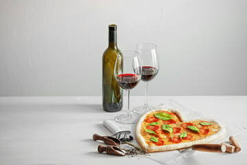 concept of romantic dinner for two with red wine and pizza in the shape of a heart. dinner for valentine's day