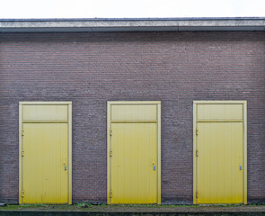 Three yellow doors in a brick wall