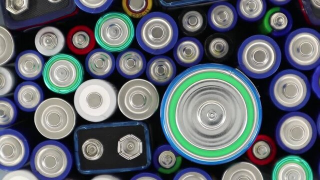 Close-up of used alkaline batteries of different types and grades. Many used batteries rotate. The harmful effects of batteries on the nature of the planet Earth and disposal