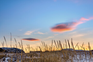 A clouds that looks like a UFO. Lenticular cloud above the ground. Arctic coast.