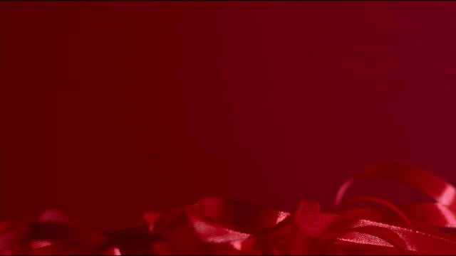 Granate shiny flowing satin ribbon falling down and fluttering on a dark red matte background. Seamless video background. New year, Christmas winter festive mood. Full Hd still high quality video 