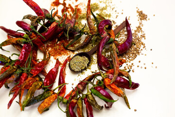 Dried red peppers and spoon with rosemary. Different spices. On a white background.