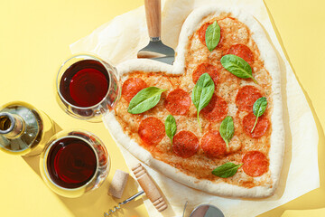 concept of romantic dinner for two with red wine and pizza in the shape of a heart. dinner for valentine's day