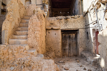 A staircase, a wood carved door and the ruins of an ancient abandoned building. Al Hamra, Oman.