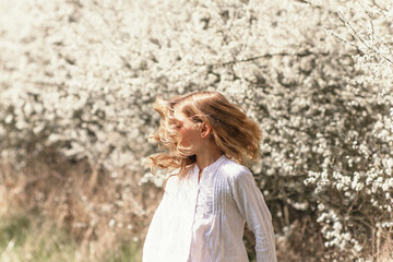 Young blond girl in white blossom in nature. Woman beautiful spring portrait with copy space
