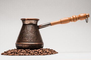 Close up shot of copper coffee pot on heap of roasted coffee beans isolated on white.