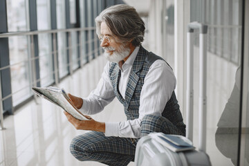 Business trip. Corporate and people concept. Male in a gray coat. Senior with a map.