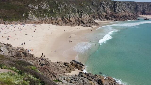 Porthcurno Beach in Cornwall with clear water and blue sky - High angle shot and tilt up 