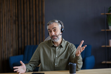 Portrait of grey-haired senior handsome man teaching online. Online education, remote working, home...