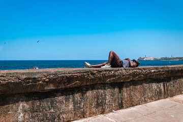 man asleep on wall by the sea