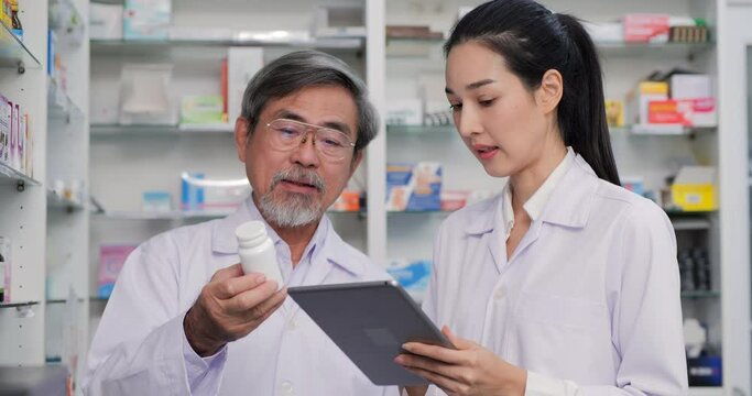Senior male doctor working with female doctor at drugstore. He doctor training female doctor about drug detail at drugstore.