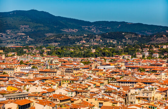 Beautiful panoramic aerial view of the historic centre of Florence surrounded by the Florentine hills, planted with olive groves and vineyards, and dotted with villas on a sunny day with a blue sky.