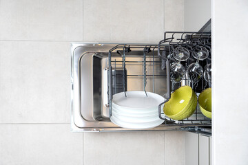 Integrated dishwaher machine loading. Open dishwasher top view.