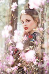 Fototapeta premium Japanese-style girl in a flowering forest among pink flowers in spring