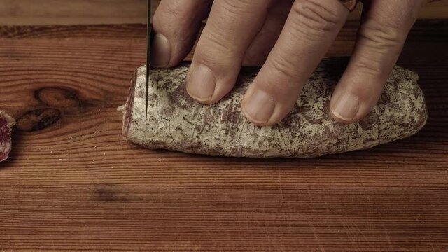 Mani che affettano il salame